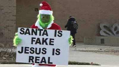 Image for story: Grinch tries to steal Christmas, stands in front of elementary school with 'Santa Is Fake' sign