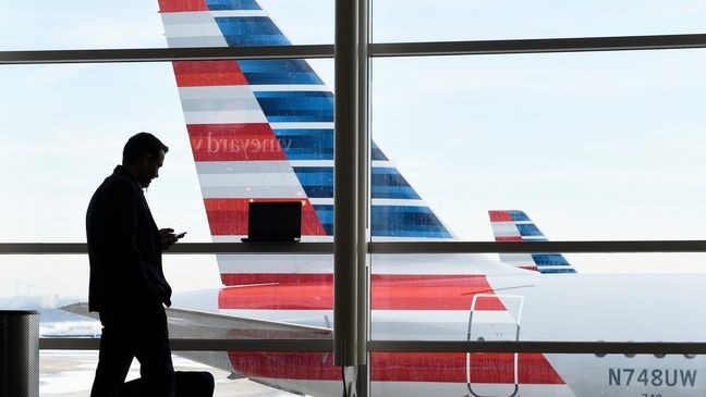 FILE - A passenger talks on the phone with American Airlines jets parked behind him at Washington's Ronald Reagan National Airport. (WWMT/AP Photo/Susan Walsh, File)